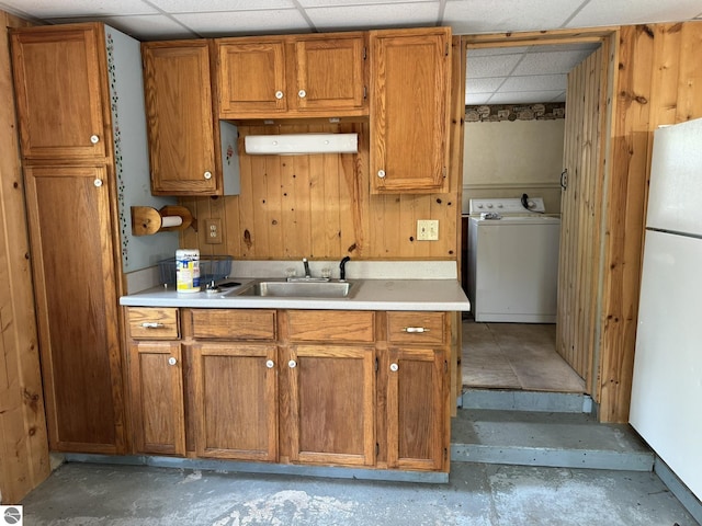 11748 NE Franklin St, Kalkaska, MI 49646 - kitchen with washer / dryer, a paneled ceiling, concrete flooring, freestanding refrigerator, and brown cabinets