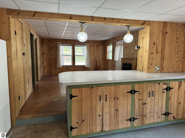 11748 NE Franklin St, Kalkaska, MI 49646 - kitchen featuring wooden walls, light countertops, a paneled ceiling, hanging light fixtures, and a peninsula