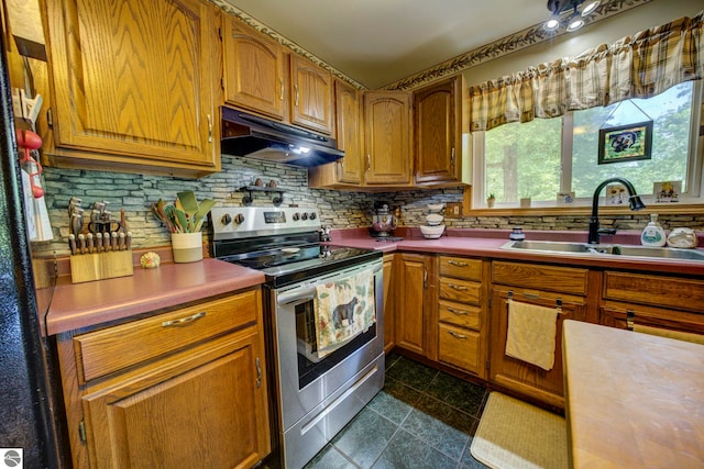 3721 W 18th Rd, Mesick, MI 49668 - kitchen with stainless steel electric stove, under cabinet range hood, tasteful backsplash, brown cabinets, and dark tile patterned floors