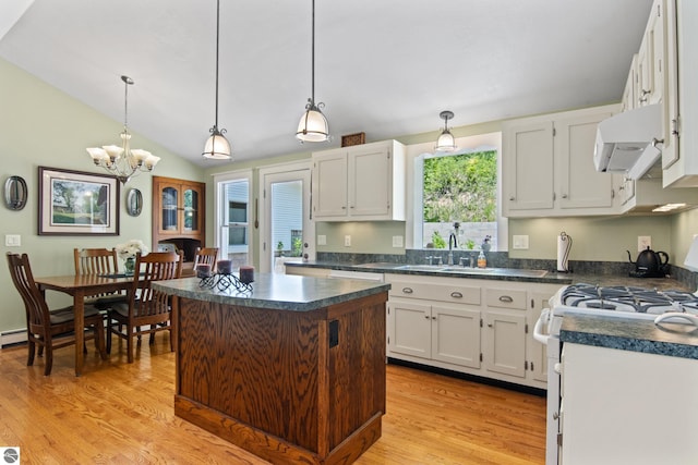 1740 Setterbo Rd, Suttons Bay, MI 49682 - kitchen with extractor fan, light wood finished floors, dark countertops, a chandelier, and white cabinetry