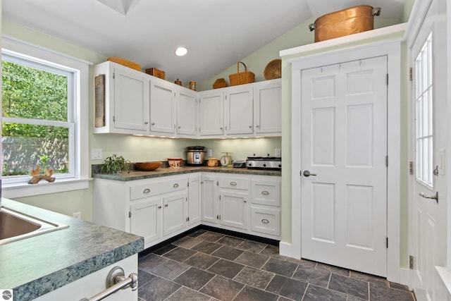 1740 Setterbo Rd, Suttons Bay, MI 49682 - kitchen featuring white cabinetry, lofted ceiling, recessed lighting, and dark stone finish floors