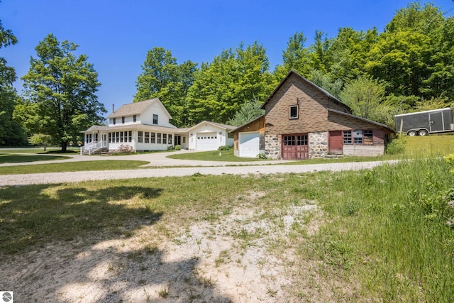 1740 Setterbo Rd, Suttons Bay, MI 49682 - view of front of home with stone siding, a detached garage, and a front lawn