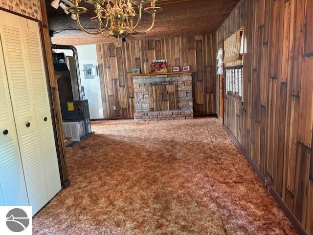 4161 Elbow Lake Rd, Prescott, MI 48756 - unfurnished living room featuring carpet floors, a chandelier, wood walls, and a fireplace