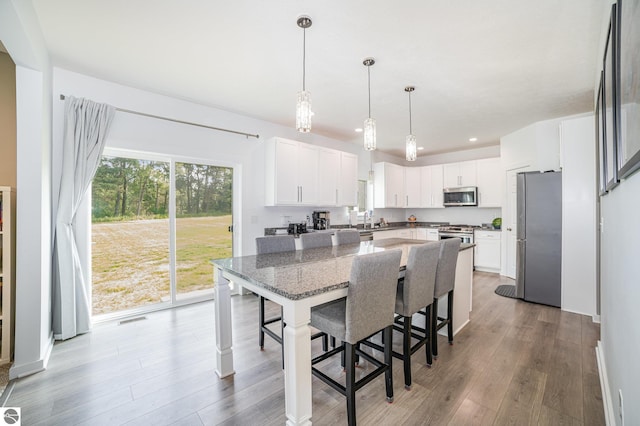 3468 Kali Ln, Alma, MI 48801 - kitchen with appliances with stainless steel finishes, wood finished floors, a kitchen bar, dark stone countertops, and white cabinetry
