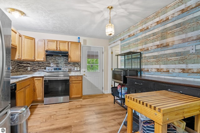 2733 Windcrest Ln, Traverse City, MI 49686 - kitchen featuring stainless steel appliances, range hood, light countertops, wood walls, and decorative backsplash