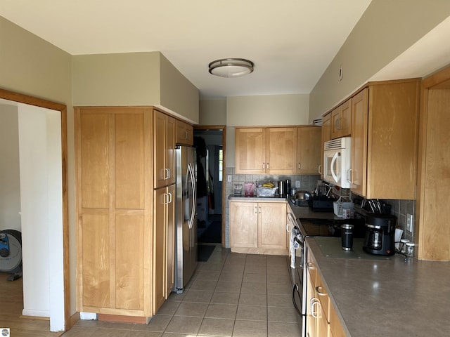 1339 S Melita Rd, Sterling, MI 48659 - kitchen featuring appliances with stainless steel finishes, decorative backsplash, light tile patterned floors, and dark countertops