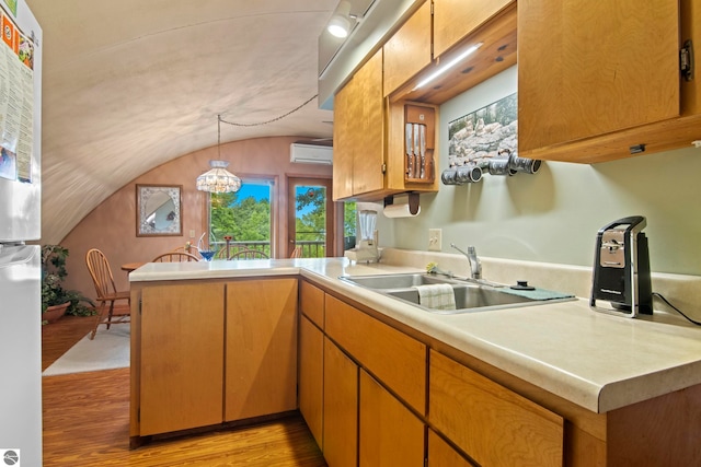 9420 E Traverse Hwy, Traverse City, MI 49684 - kitchen featuring a peninsula, vaulted ceiling, an AC wall unit, light wood-type flooring, and light countertops