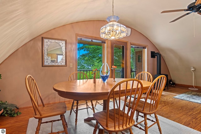9420 E Traverse Hwy, Traverse City, MI 49684 - dining room featuring a wood stove, wood finished floors, lofted ceiling, a ceiling fan, and a chandelier