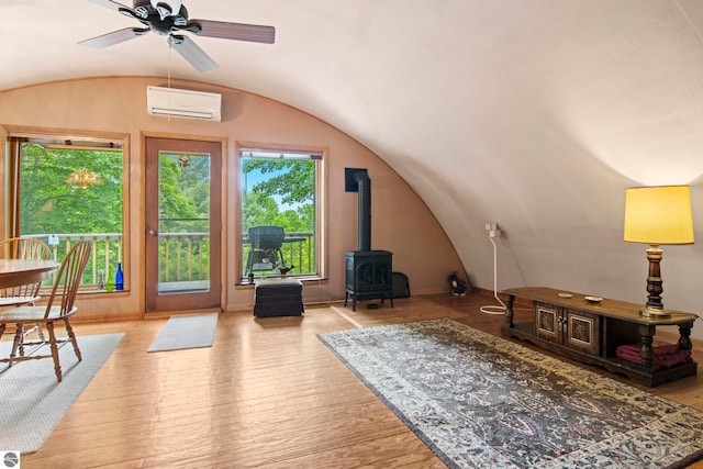 9420 E Traverse Hwy, Traverse City, MI 49684 - living room with a wall mounted air conditioner, a wood stove, lofted ceiling, healthy amount of natural light, and ceiling fan