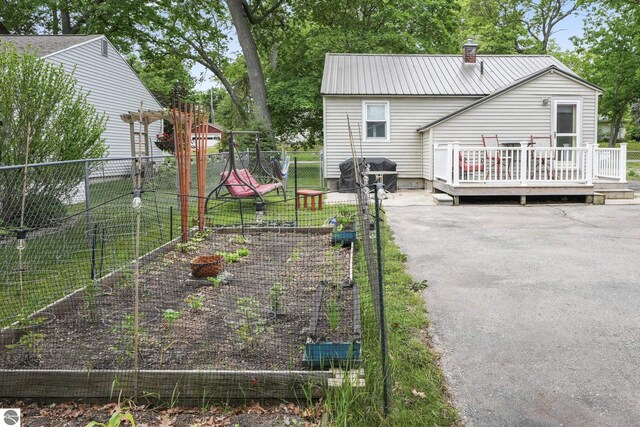 821 Indian Trail Blvd, Traverse City, MI 49686 - back of house with a vegetable garden, a deck, a chimney, and a metal roof
