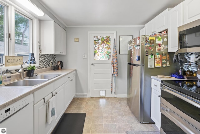 821 Indian Trail Blvd, Traverse City, MI 49686 - kitchen with stainless steel appliances, decorative backsplash, white cabinets, light countertops, and ornamental molding