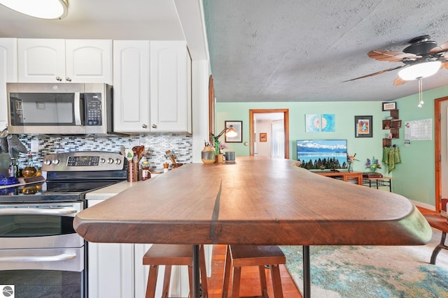 821 Indian Trail Blvd, Traverse City, MI 49686 - kitchen featuring stainless steel appliances, a ceiling fan, white cabinetry, backsplash, and a peninsula