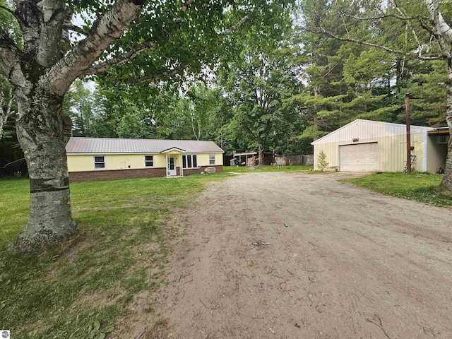 622 W Houghton Lake Rd, Lake City, MI 49651 - ranch-style house with driveway, a garage, an outdoor structure, a metal roof, and view of scattered trees
