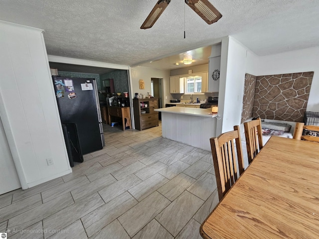 622 W Houghton Lake Rd, Lake City, MI 49651 - kitchen featuring freestanding refrigerator, ceiling fan, a textured ceiling, range, and a peninsula