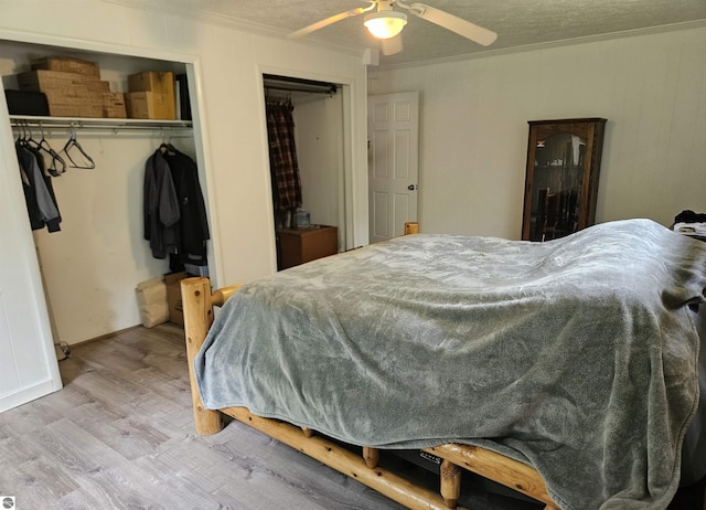622 W Houghton Lake Rd, Lake City, MI 49651 - bedroom featuring crown molding, wood finished floors, two closets, a textured ceiling, and a ceiling fan