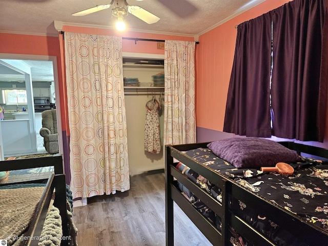 622 W Houghton Lake Rd, Lake City, MI 49651 - bedroom with wood finished floors, crown molding, a textured ceiling, ceiling fan, and a closet