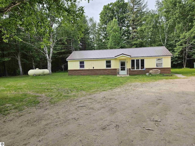 622 W Houghton Lake Rd, Lake City, MI 49651 - view of front facade featuring a metal roof, a front lawn, and brick siding