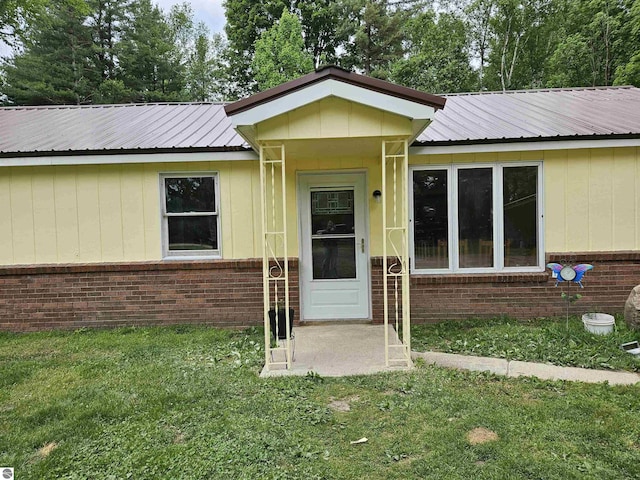 622 W Houghton Lake Rd, Lake City, MI 49651 - property entrance with a lawn, brick siding, and a metal roof