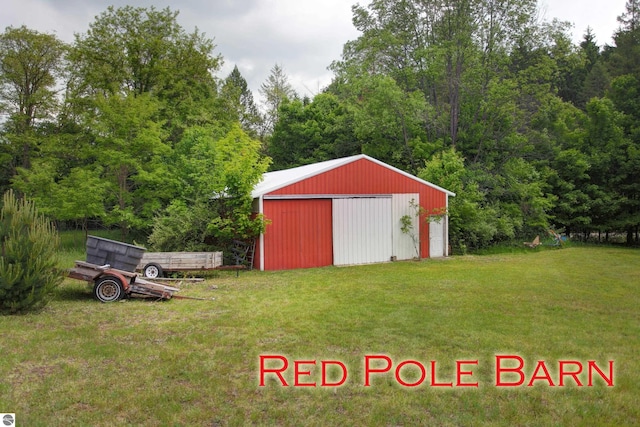 8124 Crisp Rd, Williamsburg, MI 49690 - view of green lawn featuring an outbuilding, a garage, and a view of trees