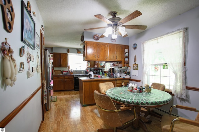 8124 Crisp Rd, Williamsburg, MI 49690 - kitchen featuring brown cabinetry, a peninsula, a textured ceiling, freestanding refrigerator, and light wood-style flooring