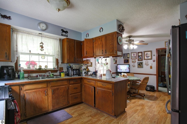 8124 Crisp Rd, Williamsburg, MI 49690 - kitchen featuring freestanding refrigerator, stove, a peninsula, light wood-style flooring, and a textured ceiling
