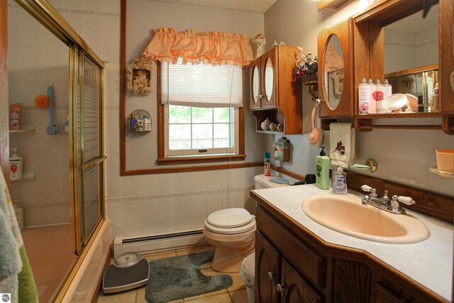 8124 Crisp Rd, Williamsburg, MI 49690 - bathroom with baseboard heating, vanity, tile patterned floors, combined bath / shower with glass door, and tile walls