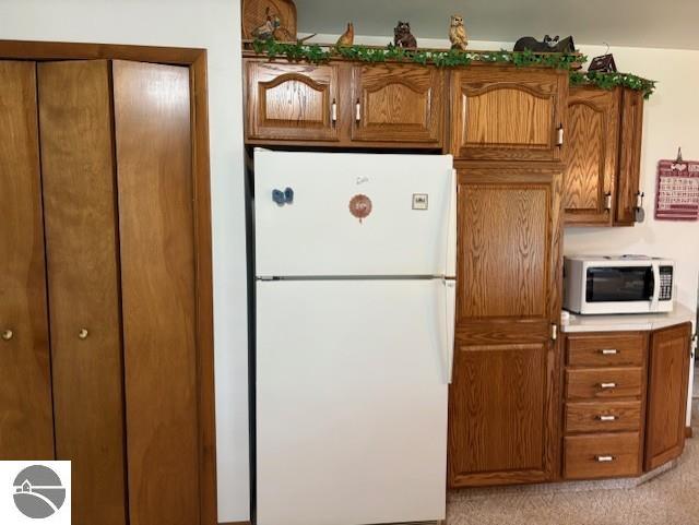 2615 Antelope Trl, West Branch, MI 48661 - kitchen featuring white appliances, brown cabinetry, and light carpet