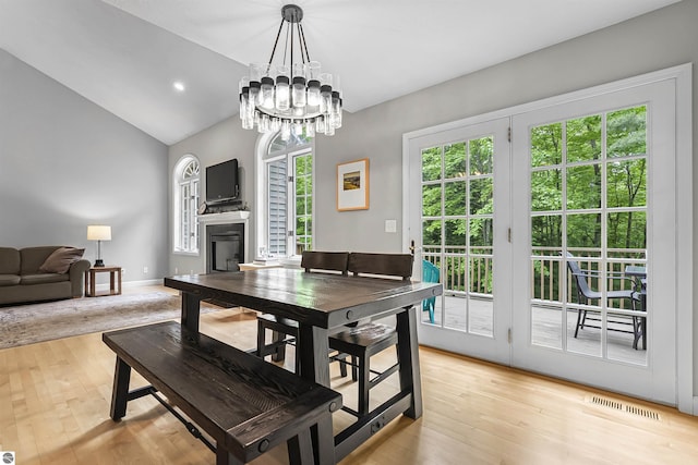 4180 Pintail Dr, Traverse City, MI 49696 - dining area featuring healthy amount of natural light, a fireplace, lofted ceiling, light wood-type flooring, and a chandelier