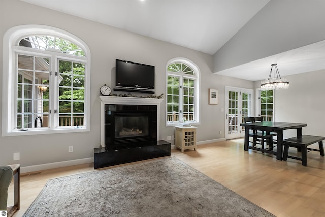 4180 Pintail Dr, Traverse City, MI 49696 - living room featuring wood finished floors, lofted ceiling, a glass covered fireplace, a chandelier, and french doors