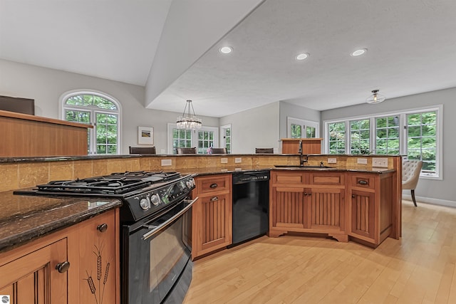 4180 Pintail Dr, Traverse City, MI 49696 - kitchen featuring black appliances, recessed lighting, brown cabinetry, dark stone counters, and light wood-style flooring