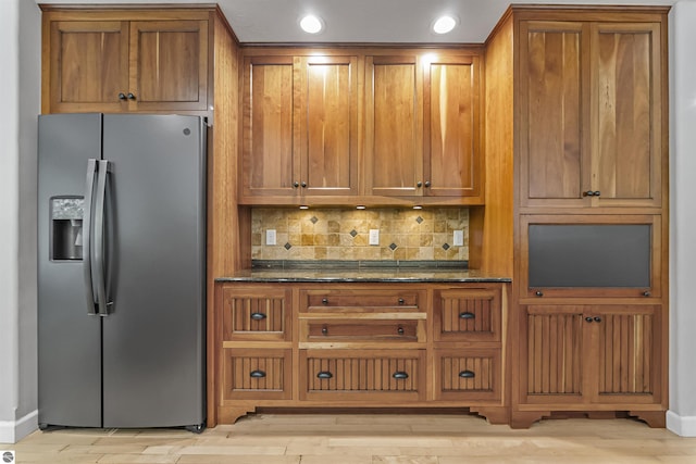 4180 Pintail Dr, Traverse City, MI 49696 - kitchen featuring stainless steel refrigerator with ice dispenser, brown cabinets, dark stone countertops, backsplash, and recessed lighting
