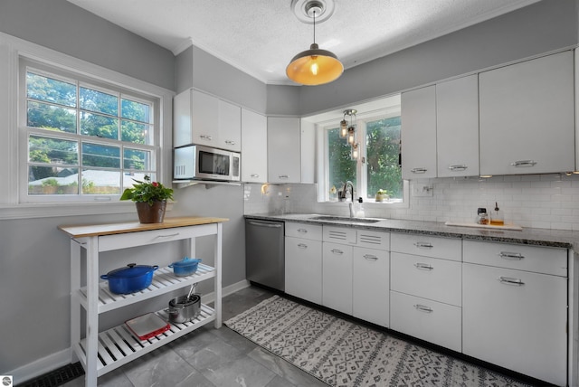 701 Sixth St, Traverse City, MI 49684 - kitchen featuring appliances with stainless steel finishes, a textured ceiling, tasteful backsplash, white cabinets, and dark stone counters