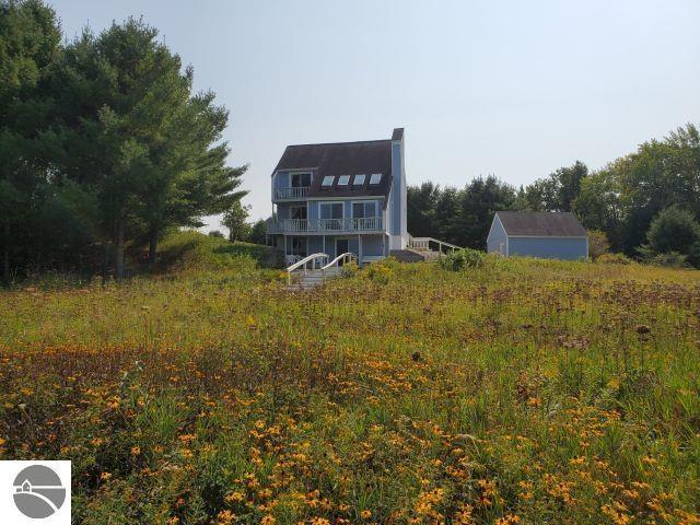 5736 Greenwood Rd, Gladwin, MI 48624 - back of house featuring a balcony, a gambrel roof, and a chimney