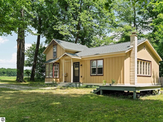 10090 E 48th Rd, Cadillac, MI 49601 - view of front of house featuring roof with shingles, board and batten siding, and a front lawn