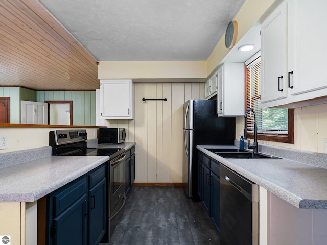 10090 E 48th Rd, Cadillac, MI 49601 - kitchen with stainless steel appliances, blue cabinets, white cabinetry, dark wood finished floors, and wood walls