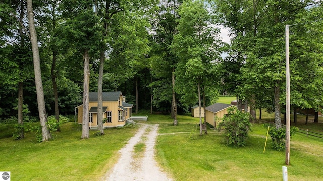 10090 E 48th Rd, Cadillac, MI 49601 - view of front facade with dirt driveway, a storage shed, and view of scattered trees