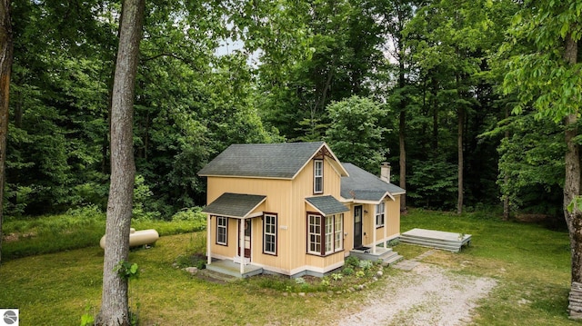 10090 E 48th Rd, Cadillac, MI 49601 - view of front of house featuring a shingled roof, driveway, a chimney, a detached carport, and a front lawn