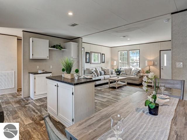 11399 Union St, Fife Lake, MI 49633 - kitchen with wood finished floors, white cabinetry, open shelves, a kitchen island, and open floor plan