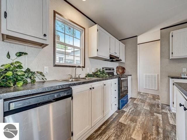 11399 Union St, Fife Lake, MI 49633 - kitchen with stainless steel appliances, dark countertops, dark wood-style flooring, tasteful backsplash, and white cabinets