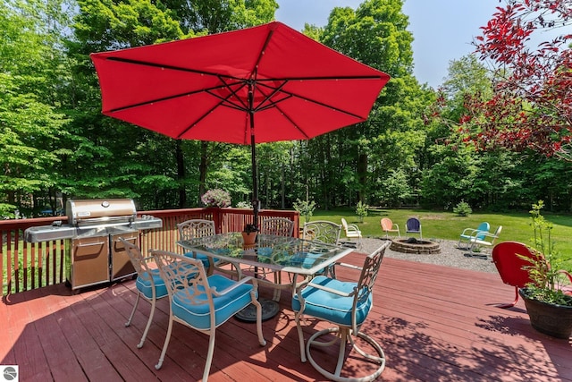 2491 Holland Cir, Traverse City, MI 49685 - wooden terrace with a fire pit, outdoor dining space, a yard, and view of wooded area