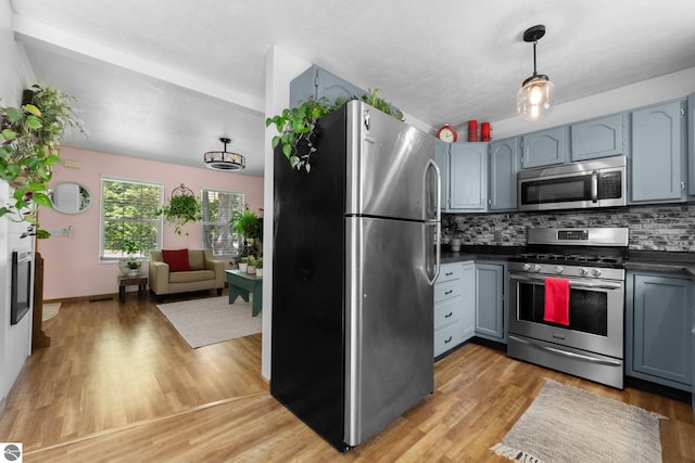 2491 Holland Cir, Traverse City, MI 49685 - kitchen with appliances with stainless steel finishes, dark countertops, tasteful backsplash, and light wood-style flooring
