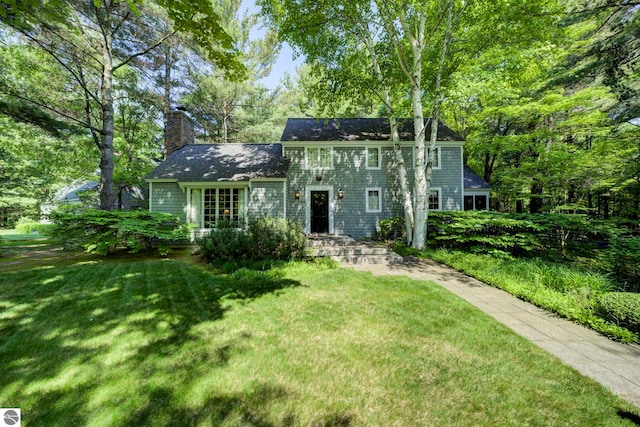 4079 E Oxford Dr, Leland, MI 49654 - colonial-style house featuring a chimney and a front lawn