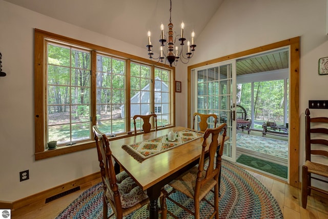 4079 E Oxford Dr, Leland, MI 49654 - dining room featuring a chandelier, vaulted ceiling, and wood finished floors