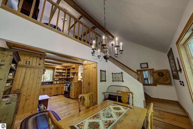 4079 E Oxford Dr, Leland, MI 49654 - dining space featuring light wood-style flooring, a chandelier, stairs, and lofted ceiling