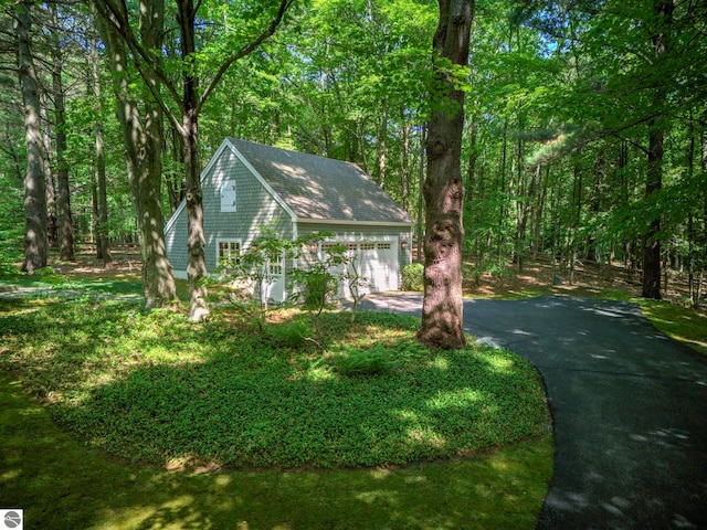 4079 E Oxford Dr, Leland, MI 49654 - view of front of property with asphalt driveway, a forest view, and a garage
