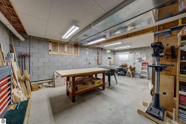 4079 E Oxford Dr, Leland, MI 49654 - below grade area with a workshop area, concrete block wall, baseboard heating, electric panel, and a paneled ceiling
