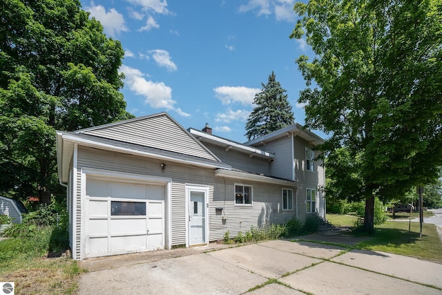 503 N Kinney Ave, Mount Pleasant, MI 48858 - view of front of home featuring an attached garage, concrete driveway, and a chimney