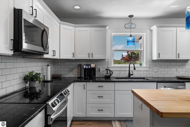 6330 Lund Rd SW, Fife Lake, MI 49633 - kitchen with stainless steel appliances, butcher block counters, hanging light fixtures, white cabinets, and backsplash