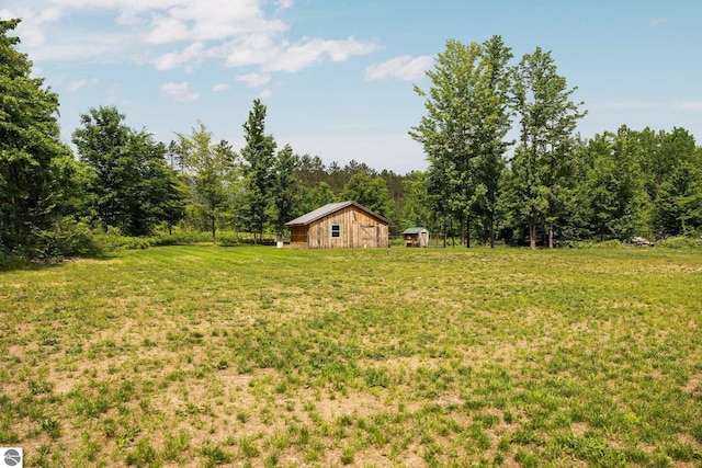 6330 Lund Rd SW, Fife Lake, MI 49633 - view of green lawn featuring an outdoor structure and a view of trees