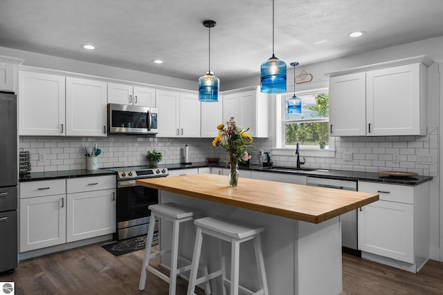 6330 Lund Rd SW, Fife Lake, MI 49633 - kitchen with appliances with stainless steel finishes, butcher block counters, a breakfast bar area, dark wood-type flooring, and recessed lighting
